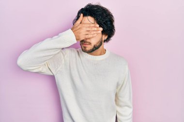 Yakışıklı, beyaz süveter giyen, gözlerini kapayan, ciddi ve üzgün görünen bir İspanyol. Görme, saklama ve reddetme konsepti 