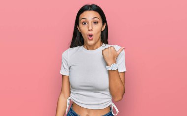 Gündelik beyaz tişört giyen genç İspanyol kız elleri yana doğru işaret ederek şaşırdı, ağzı açık hayret içinde kaldı.. 