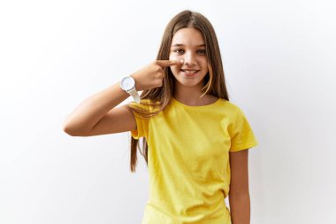 Genç esmer kız izole edilmiş arka planda yan yana duruyor. El ve burunla işaret ediyor. Neşeli bir şekilde gülümsüyor. güzellik konsepti 