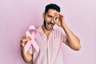 Elinde pembe kanser kurdelesi olan genç İspanyol adam gülümsüyor. Mutluluktan gülümsüyor. 