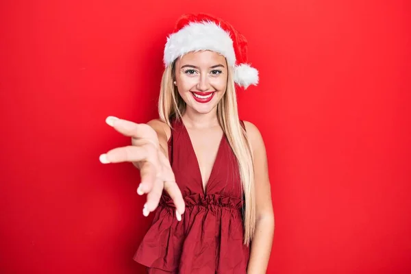 Молодая Блондинка Рождественской Шляпе Дружеской Улыбкой Предлагает Рукопожатие Качестве Приветствия — стоковое фото