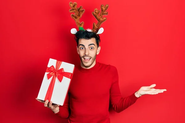Fiatal Spanyol Férfi Visel Aranyos Karácsonyi Rénszarvas Szarv Gazdaság Ajándékok — Stock Fotó