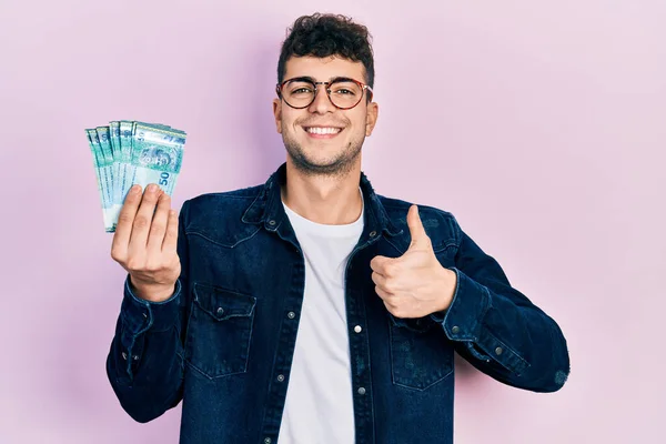 Fiatal Spanyol Férfi Kezében Malajziai Ringgit Bankjegy Mosolyogva Boldog Pozitív — Stock Fotó