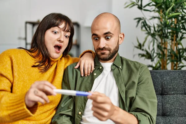 Unga Latinamerikanska Par Överraskade Håller Graviditetstest Sitter Soffan Hemma — Stockfoto