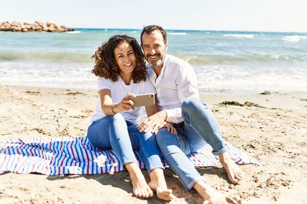 Orta Yaşlı Spanyol Çift Kumsalda Havlunun Üzerinde Oturan Akıllı Telefonun — Stok fotoğraf