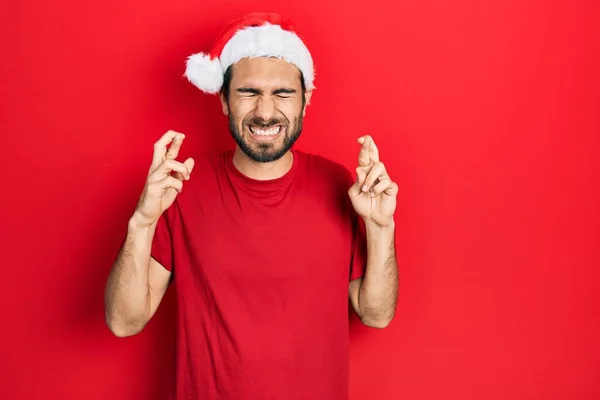 Молодий Іспаномовний Чоловік Різдвяному Капелюсі Жестикулює Палець Схрещеним Усміхненим Надією — стокове фото