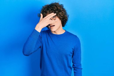 Yakışıklı genç adam, günlük kıyafetler ve gözlük takıyor. Şoka giriyor, yüzünü ve gözlerini kapatıyor. Utanmış bir ifadeyle parmaklarından bakıyor.. 