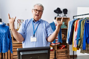 Perakende mağazasında müdür olarak çalışan yaşlı adam çılgın bir ifadeyle bağırarak elleri havada rock sembolü yapıyor. Müzik yıldızı. ağır kavram. 