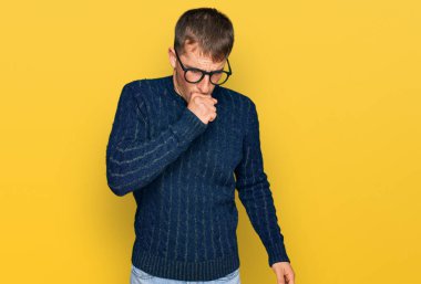 Sıradan kıyafetler ve gözlük takan genç sarışın adam kendini iyi hissetmiyor ve soğuk algınlığı veya bronşitin belirtisi olarak öksürüyor. sağlık hizmeti kavramı. 