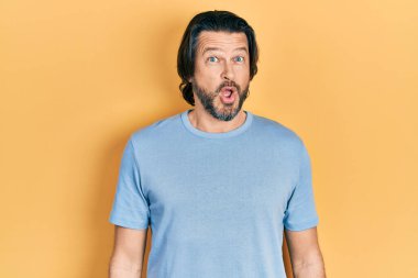 Orta yaşlı, günlük kıyafetler giyen, korku ve heyecan dolu bir yüz ifadesinden korkan ve şok olan beyaz bir adam.. 