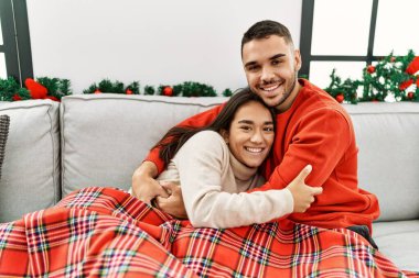 Genç İspanyol çift mutlu bir şekilde gülümsüyor ve kanepede oturuyor..