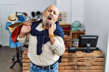 Yakışıklı bir son sınıf öğrencisi butik dükkanında diş ağrısı ya da diş ağrısı yüzünden ağzıyla dokunuyor. dişçi kavramı. 