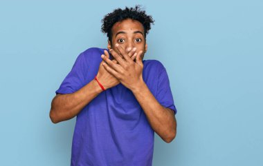 Sakallı, sıradan mor tişörtlü genç Afro-Amerikalı bir adam ağzını yanlışlıkla ellerle kapatarak şok etti. gizli kavram. 