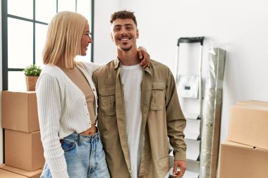 Yeni evinde mutlu bir şekilde gülümseyen ve sarılan beyaz bir çift..