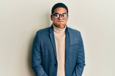 Zarif kıyafetler giyen ve gözlüklü, komik yüzlü, yanak şişiren genç, yakışıklı İspanyol adam. Havayla şişmiş ağız, çılgın bir ifade.. 