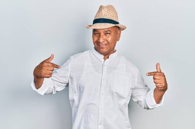 Orta yaşlı, sıradan kıyafetler giyen, şapkalı, kendine güvenen, gülümseyen, kendini gururlu ve mutlu gösteren bir adam.. 