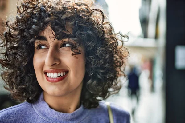 Orta Doğu 'lu genç bir kadın sokakta kendinden emin gülümsüyor.