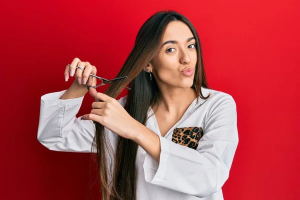 Young Hispanic Girl Cutting Hair Using Scissors Looking Camera Blowing — Stock Photo, Image