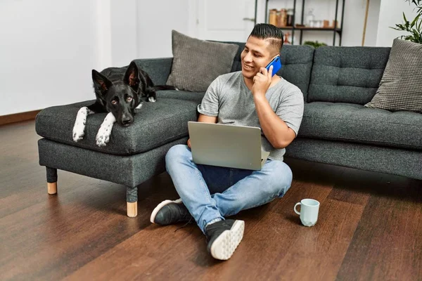 Fiatal Spanyol Férfi Használja Laptop Beszél Okostelefon Padlón Kutyával Otthon — Stock Fotó