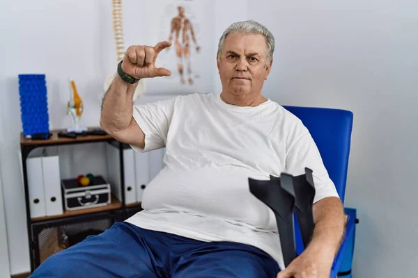 Homem Caucasiano Sênior Clínica Fisioterapia Segurando Muletas Sorrindo Gestos Confiantes — Fotografia de Stock