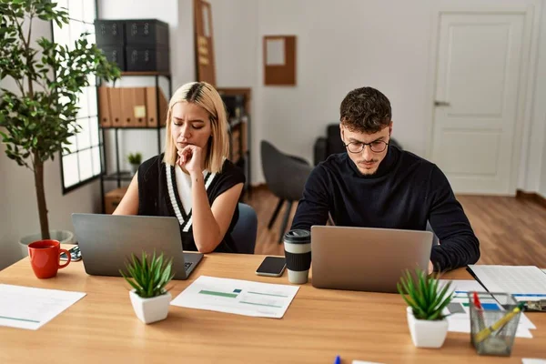 Ofiste çalışan ciddi ifadeli iki iş adamı..