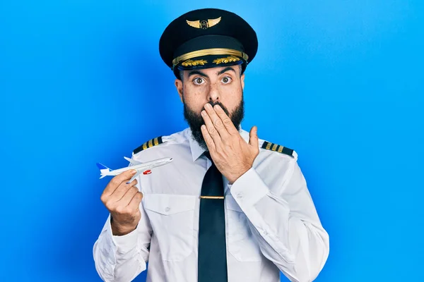 Joven Hispano Con Uniforme Piloto Sosteniendo Juguete Plano Cubriendo Boca —  Fotos de Stock