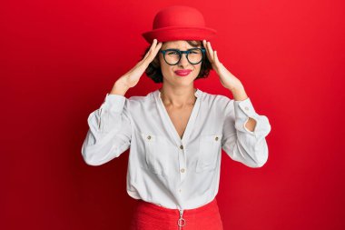 Genç esmer kadın hostes tarzı giyiniyor ve gözlük takıyor. Baş ağrısı çekiyor. Ağrı ve migren yüzünden çaresiz ve stresli. Eller başının üstünde.. 