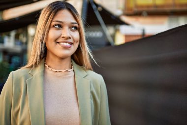 Sokakta kendinden emin gülümseyen genç Latin kadın.