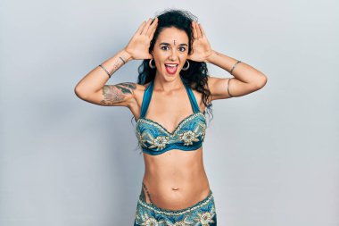 Bindi ve geleneksel göbek dansı kıyafetleri giymiş neşeli gülümseyen genç bir kadın ellerini göstererek bir yuhalamaya bakıyor. Şaşırdım ve çıktım. 