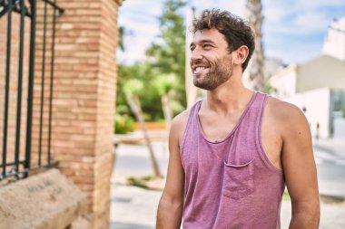 Genç İspanyol adam gülümseyerek şehirde mutlu mesut dikiliyor..