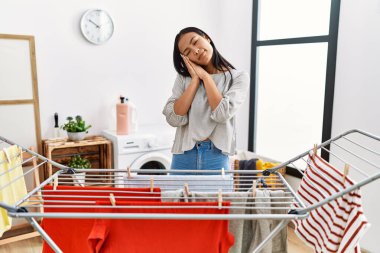 Genç İspanyol kadın çamaşır ipine temiz çamaşır koyuyor. Uyuyor, hayal kuruyor, elleriyle poz veriyor ve gözleri kapalı gülümsüyor.. 