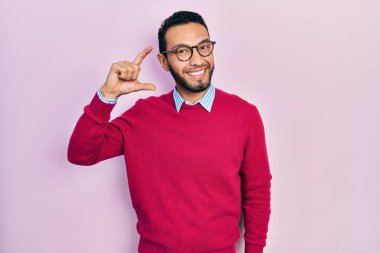 Sakallı, iş gömleği giyen, gözlüklü, gülümseyen, kendine güvenen, el hareketi yapan, parmaklarıyla işaret eden ve kameraya bakan İspanyol bir adam. ölçüm kavramı. 