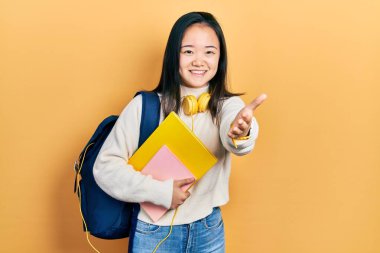 Genç Çinli kız öğrenci çantası tutuyor ve kitaplar gülümsüyor. Karşılama ve hoş geldin demek için el sıkışıyorlar. başarılı iş. 
