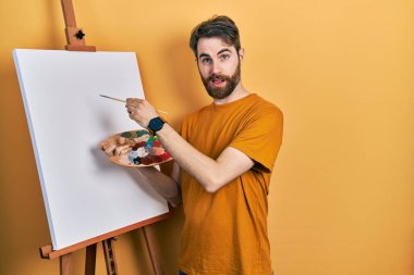 Beyaz, sakallı bir adam. Palet üstüne palet çiziyor. Şok olmuş bir yüz ifadesiyle, şüpheci ve alaycı bakıyor. 