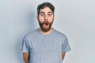 Sakallı, gri tişörtlü beyaz bir adam. Şaşırtıcı bir ifadeyle, korkuyla ve heyecanlı yüzüyle korkmuş ve şok olmuştu.. 