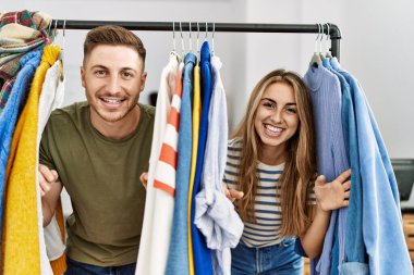 Genç İspanyol çift gülümsüyor. Moda mağazasında mutlu bir şekilde ortaya çıkıyorlar..