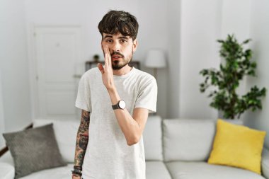 Oturma odasında sakallı İspanyol bir adam, el pençe divan duruyor. Gizli söylentiler yayıyor, kötü niyetli konuşmalar fısıldıyor. 