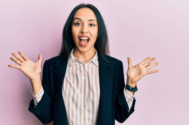 İş kıyafetleri giyen genç İspanyol kız çılgın ve başarıyı kollarını kaldırıp heyecanla haykırarak kutluyor. Kazanan konsept 