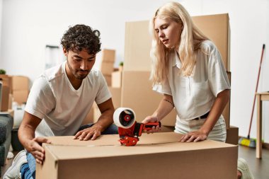 Genç ve güzel bir çift gülümsüyor. Yeni evlerinde karton kutular paketliyorlar..