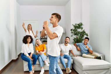 Bir grup genç arkadaş evde mikrofon kullanarak şarkı söylüyor..