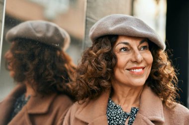 Orta yaşlı İspanyol kadın gülümseyerek şehirde mutlu mesut dikiliyor..