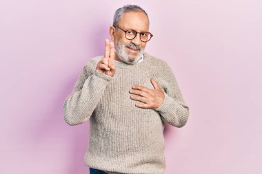 Sakallı, sıradan süveter giyen, gülümseyen, elleri göğsünde ve parmakları havada küfür eden, sadakat yemini eden yakışıklı, yaşlı bir adam. 