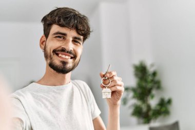 Genç İspanyol adam yeni evin anahtarını elinde tutarak fotoğraf çekiyor.