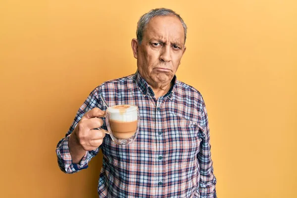 Handsome senior man with grey hair drinking a cup coffee depressed and worry for distress, crying angry and afraid. sad expression.