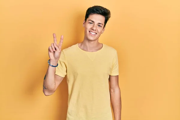 Mladý Hispánec Nenucené Žluté Tričko Usmívající Kameru Ukazující Prsty Ukazující — Stock fotografie