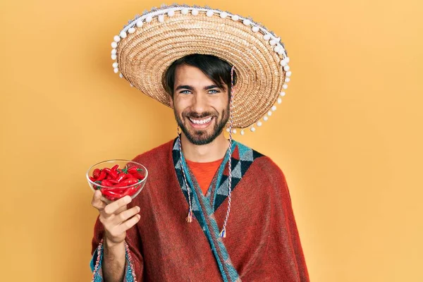 Homem Hispânico Jovem Usando Chapéu Mexicano Segurando Chili Olhando Positivo — Fotografia de Stock