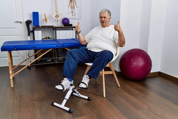 Homem Caucasiano Sênior Clínica Fisioterapia Usando Pedal Sinal Sucesso Exercitador — Fotografia de Stock