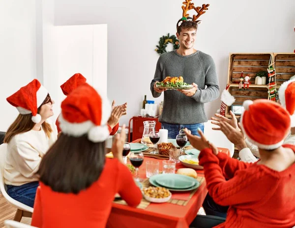 人々のグループを会議拍手とテーブルの上に座っている 男立って 家でクリスマスを祝うロースト七面鳥を保持 — ストック写真