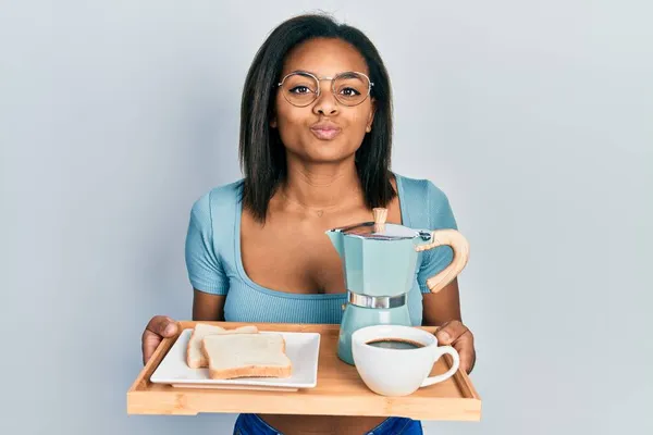 Młoda Afroamerykanka Trzymająca Tacę Śniadaniowym Jedzeniem Patrząca Kamerę Dmuchająca Pocałunek — Zdjęcie stockowe