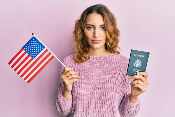 アメリカ国旗とパスポートを手にした若い白人女性は 真剣な表情でリラックスしました カメラを見ているだけで — ストック写真